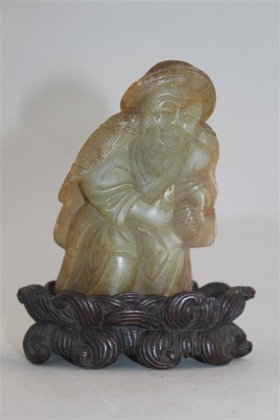 A Chinese celadon and russet skin jade figure of a fisherman, 18th / 19th century, 10cm., loss to right foot, carved wood stand